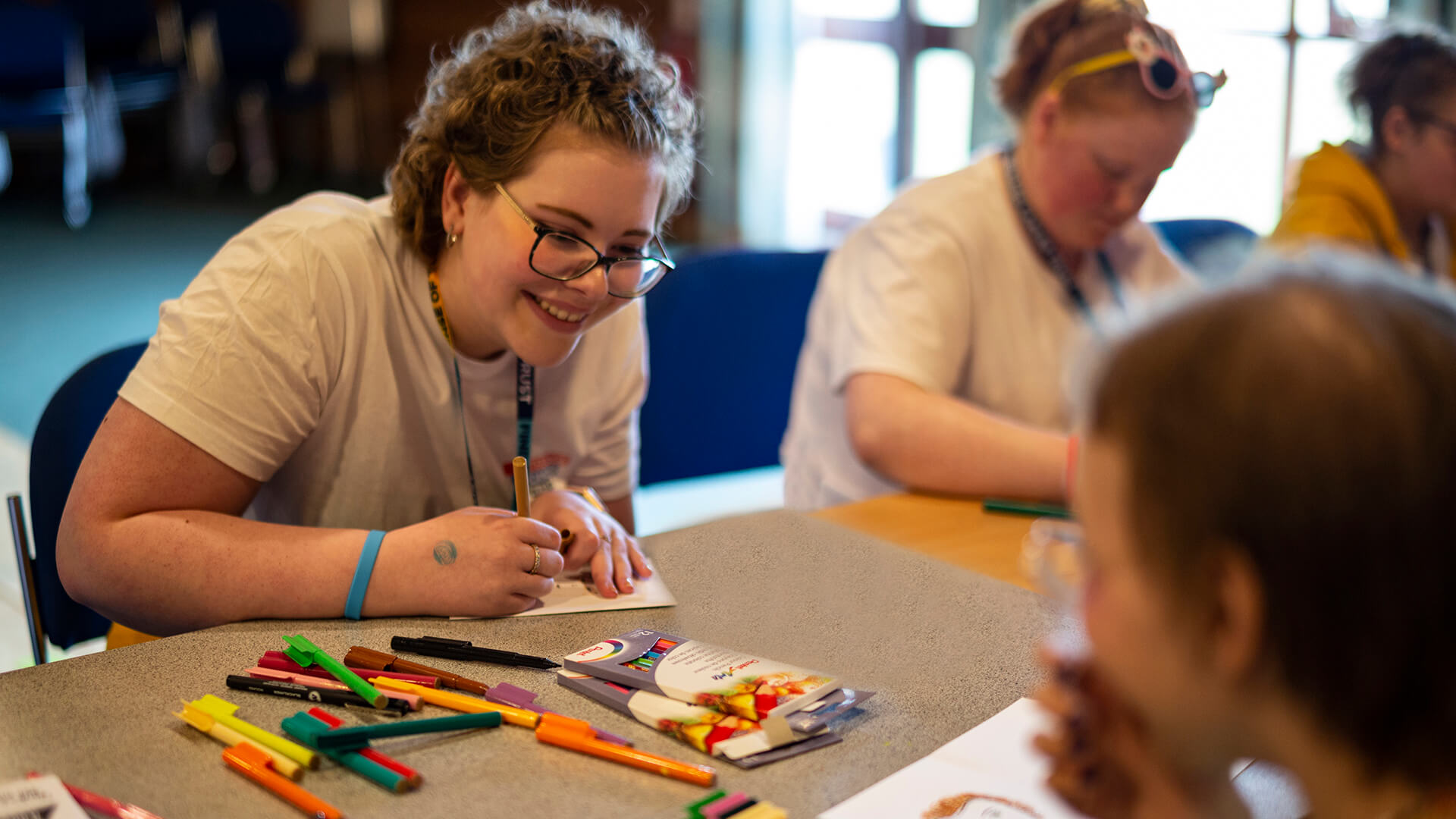 Arts and crafts: A smiling girl drawing with coloured pens at a Teenage Cancer Trust Find Your Sense of Tumour event